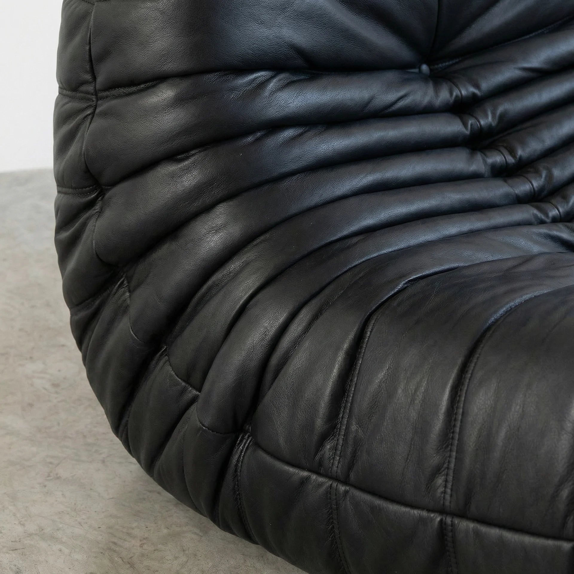 Close-up of a black leather togo sofa replica with a textured surface.