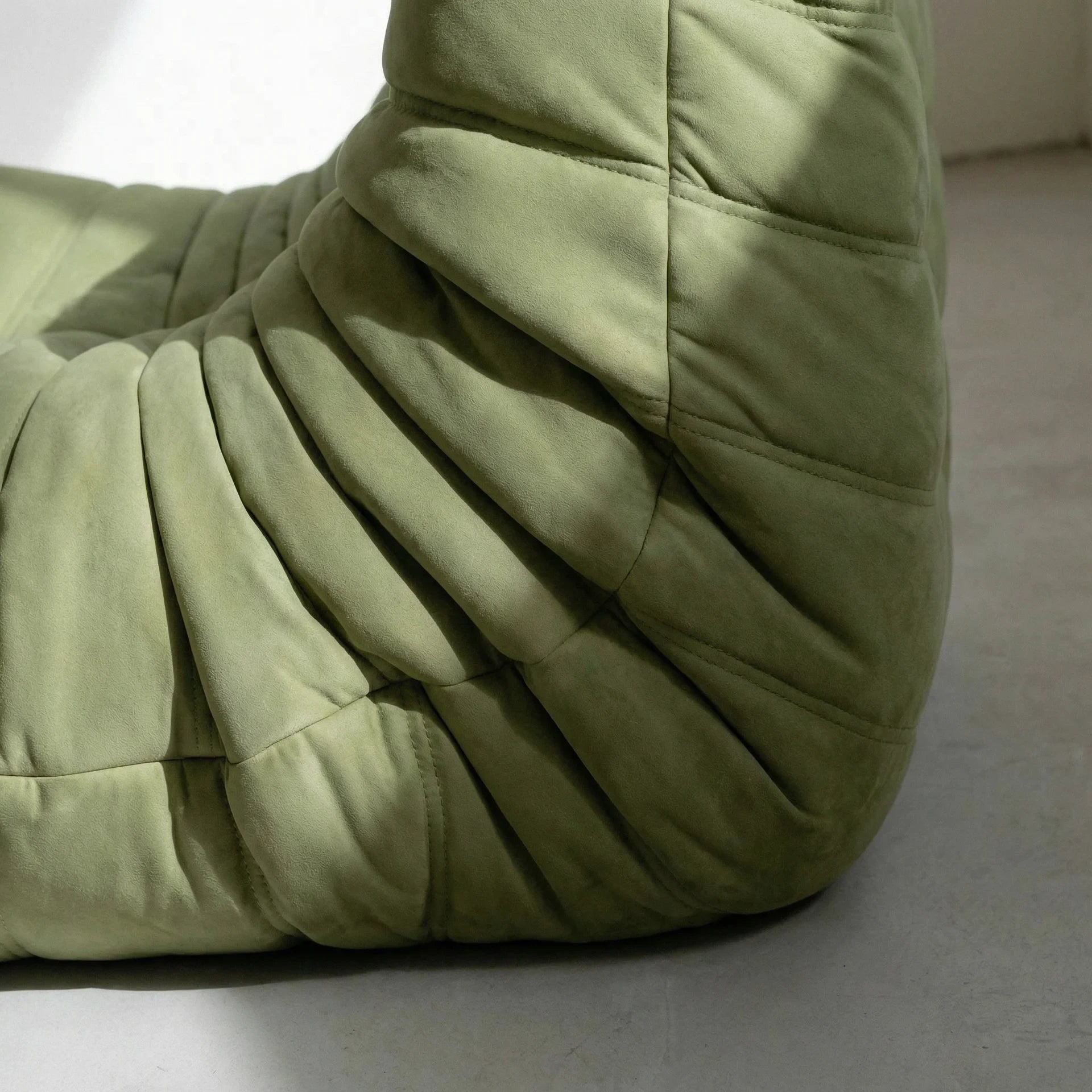 Close up of the togo chair replica in green velvet suede by vibehaus, sideangle