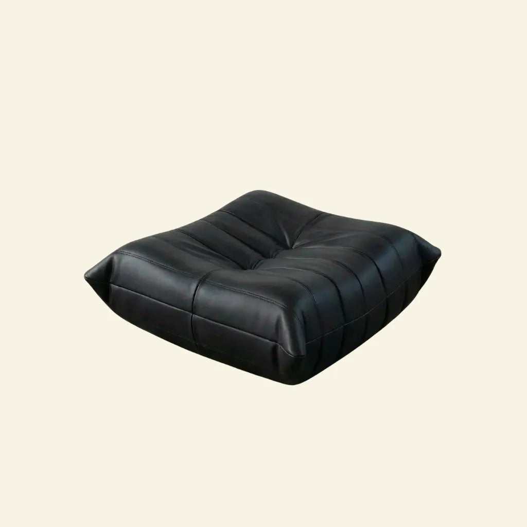 Black togo leather ottoman dupe on a beige background
