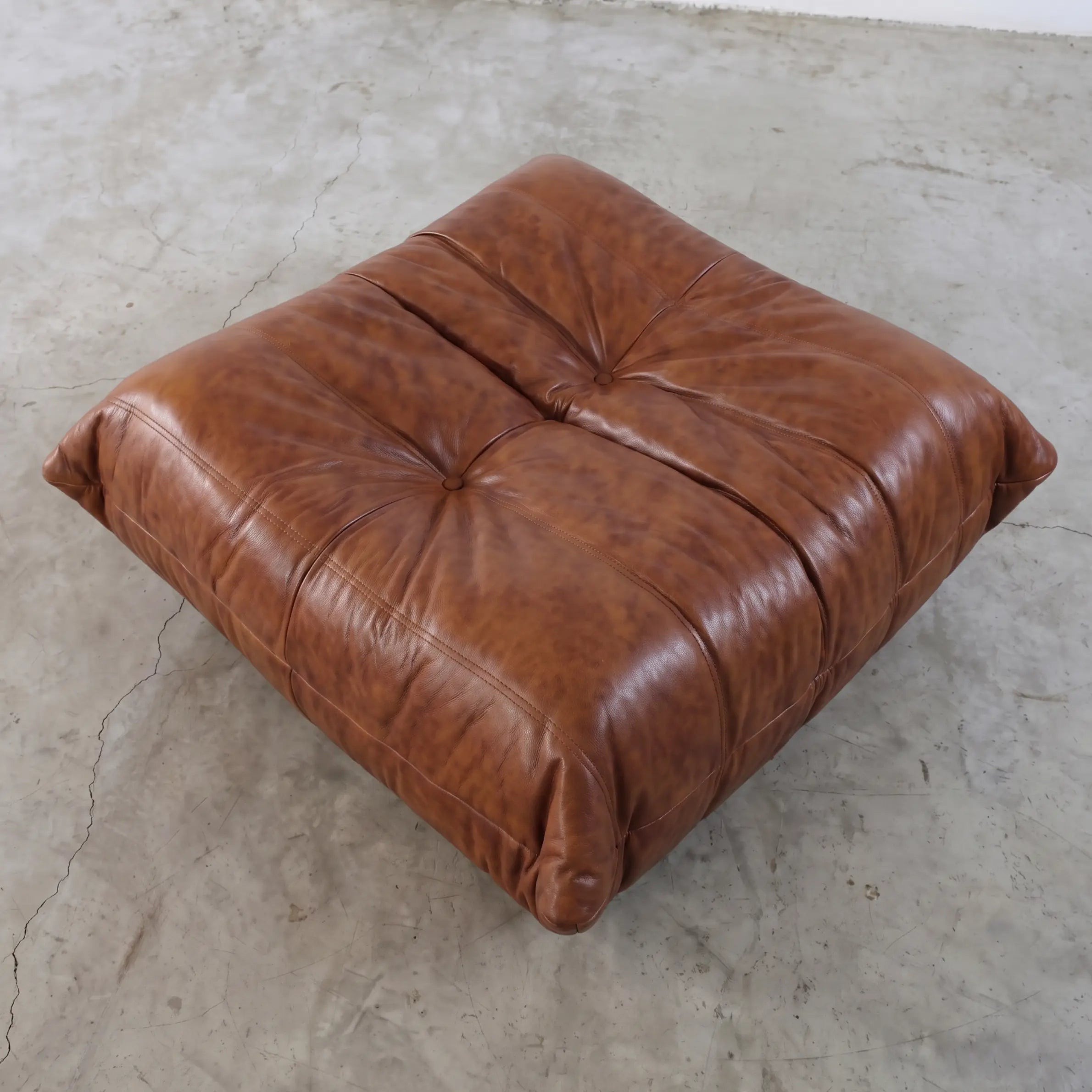 Brown togo leather ottoman dupe in a studio setting