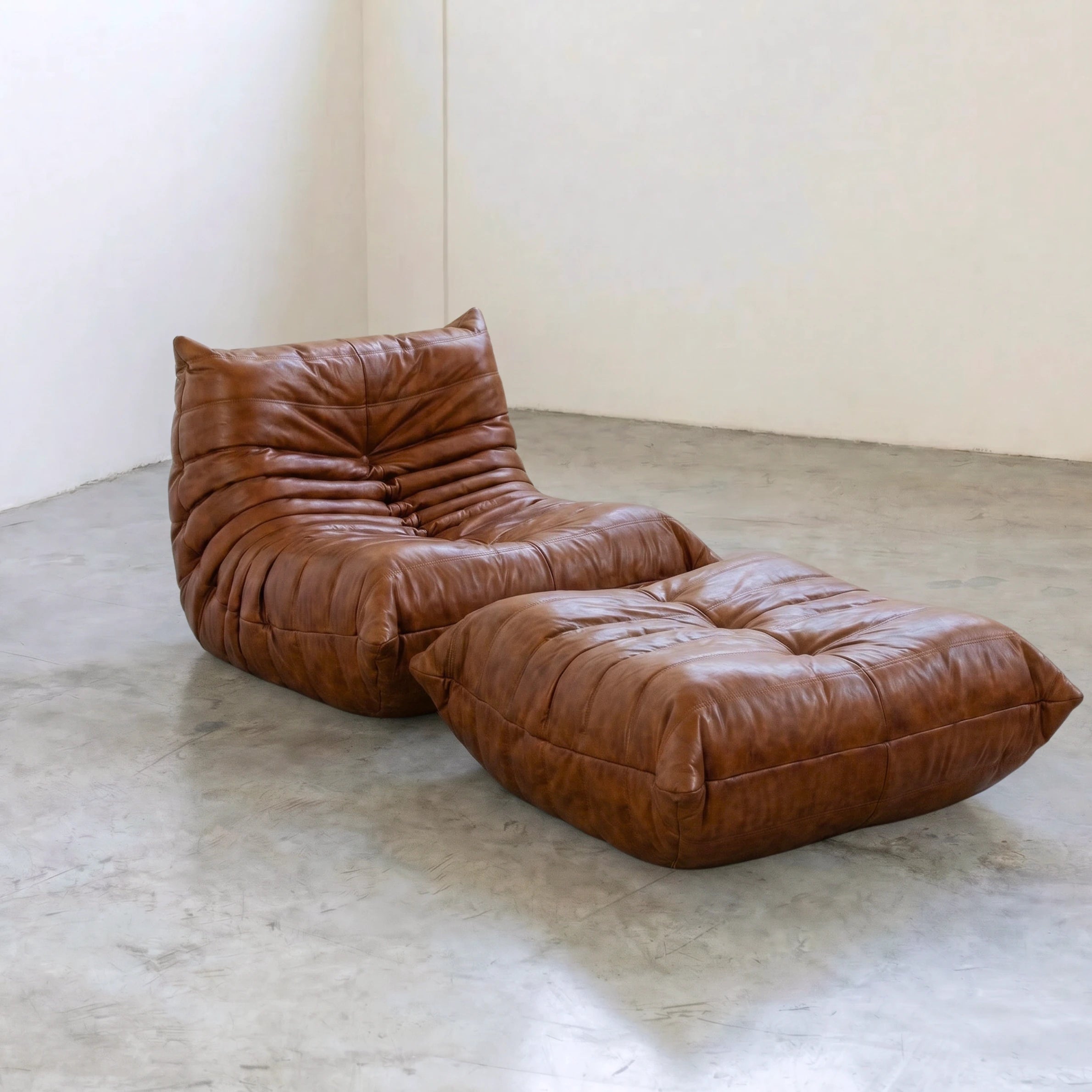 Brown togo leather ottoman and chair dupe in a studio setting