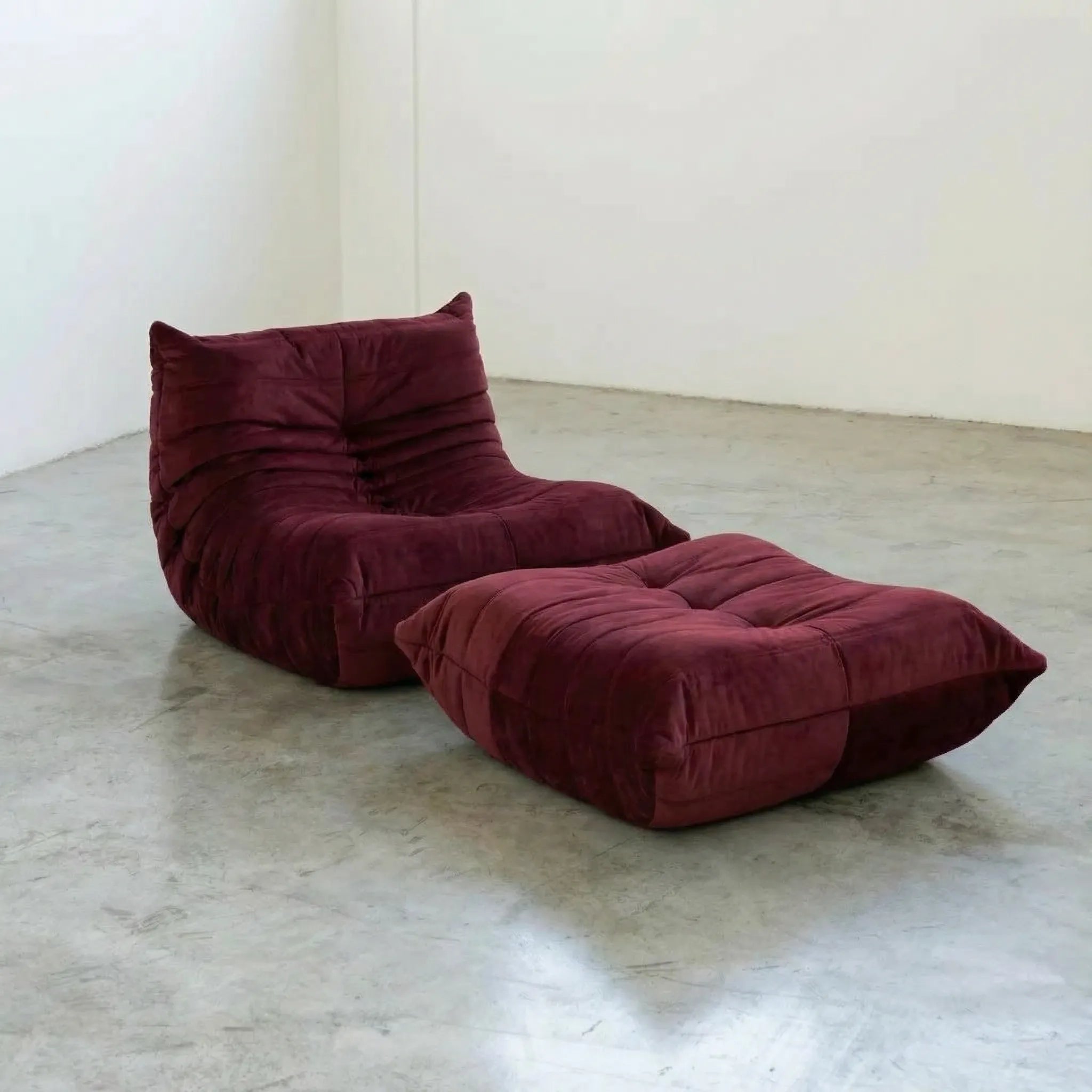 Togo chair and ottoman dupe in Burgundy Velvet Suede by Vibehaus on a concrete floor