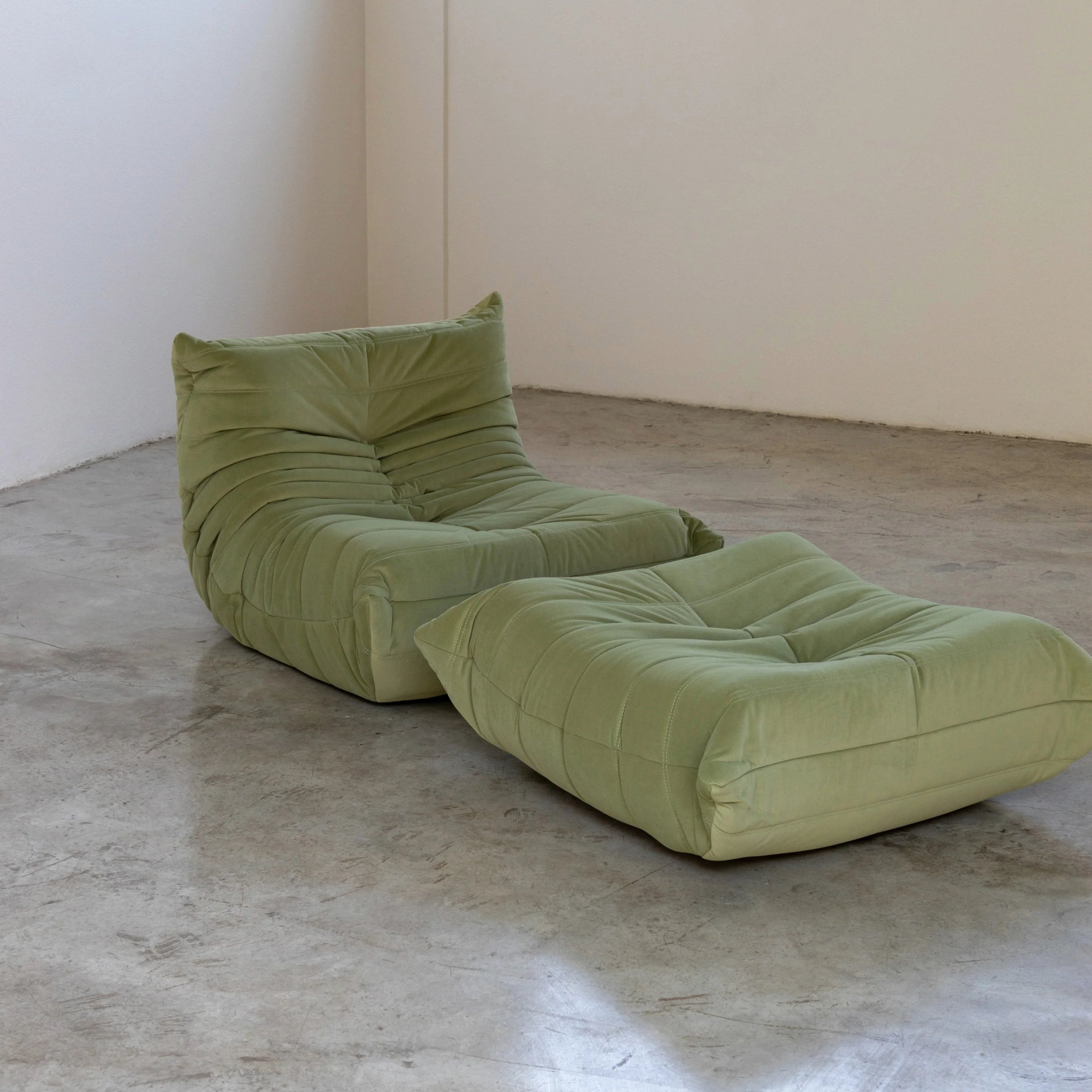 Green Velvet Suede Togo chair and ottoman dupe by Vibehaus on a concrete floor