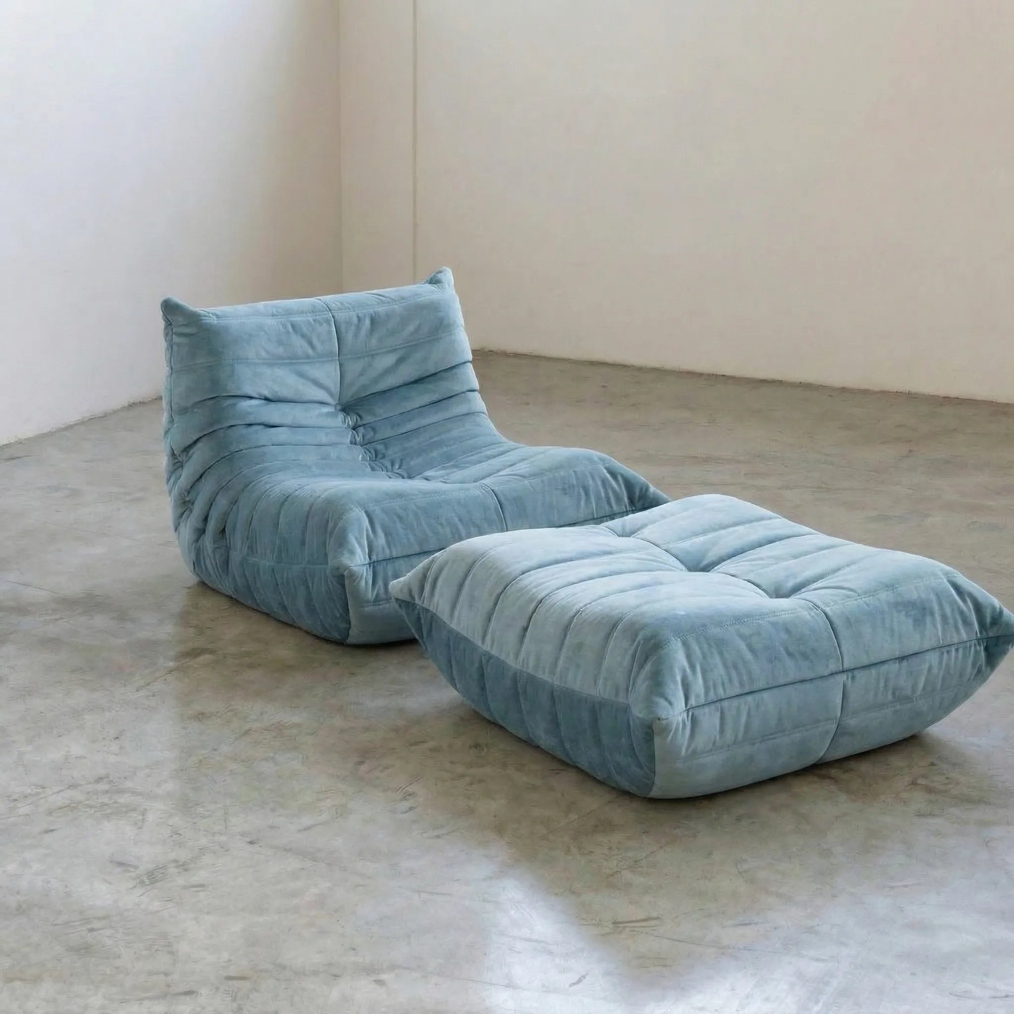 Blue velvet suede Togo chair and ottoman dupe by Vibehaus on a concrete floor
