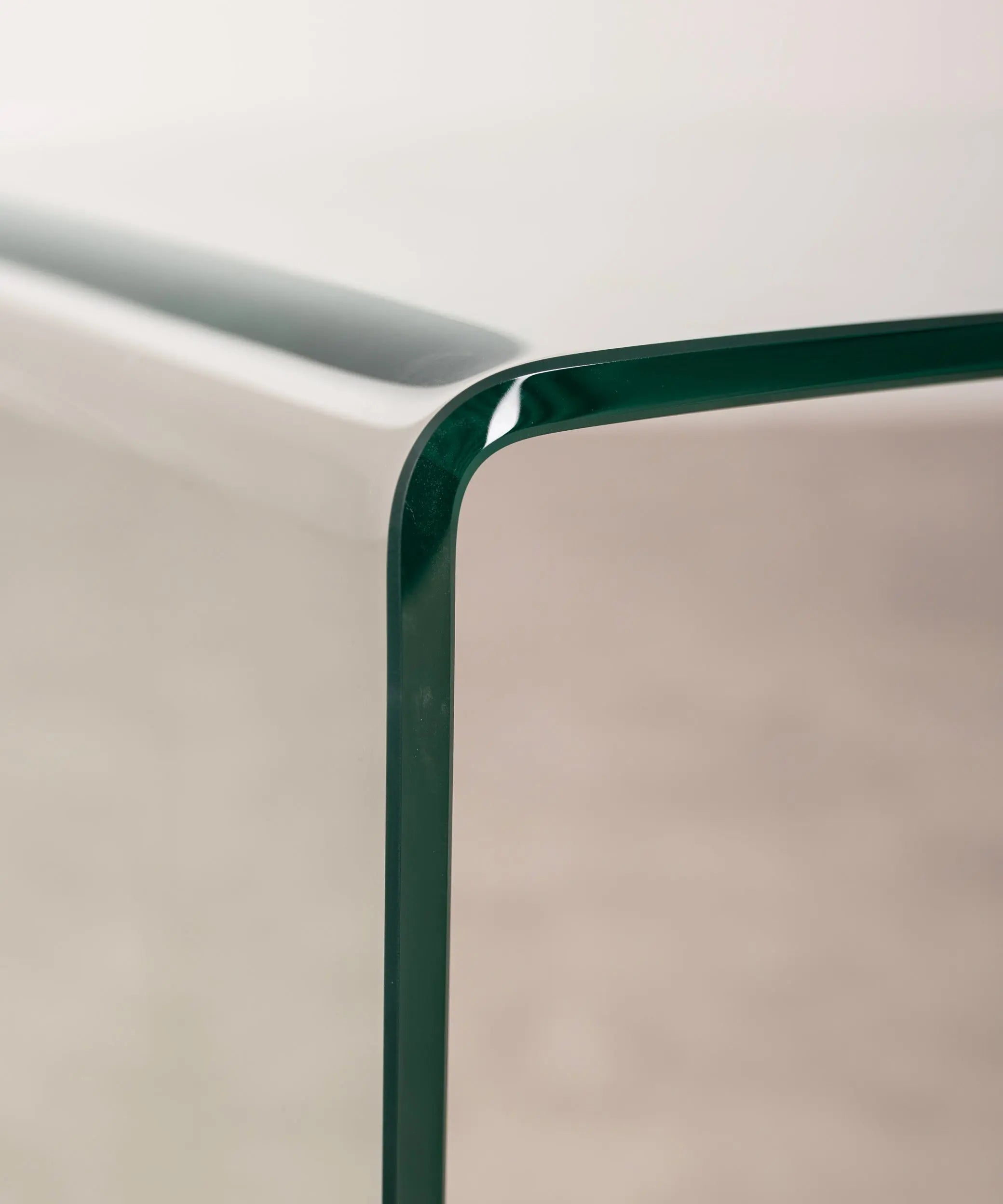 Close-up of the transparent c-shaped side table against a neutral background