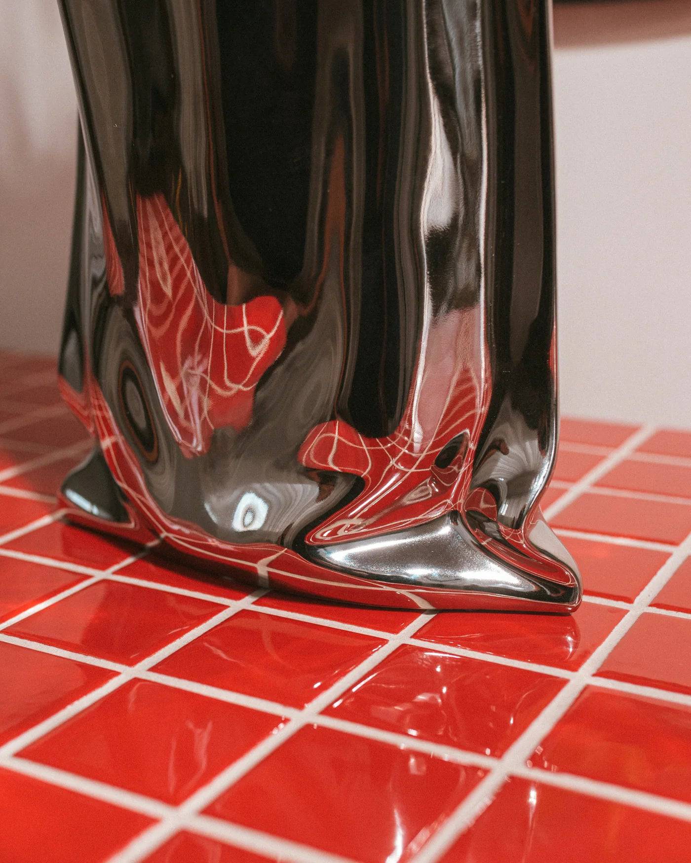Modern chrome vase made of ceramic and porcelain, featuring a reflective metallic finish and artistic silhouette.