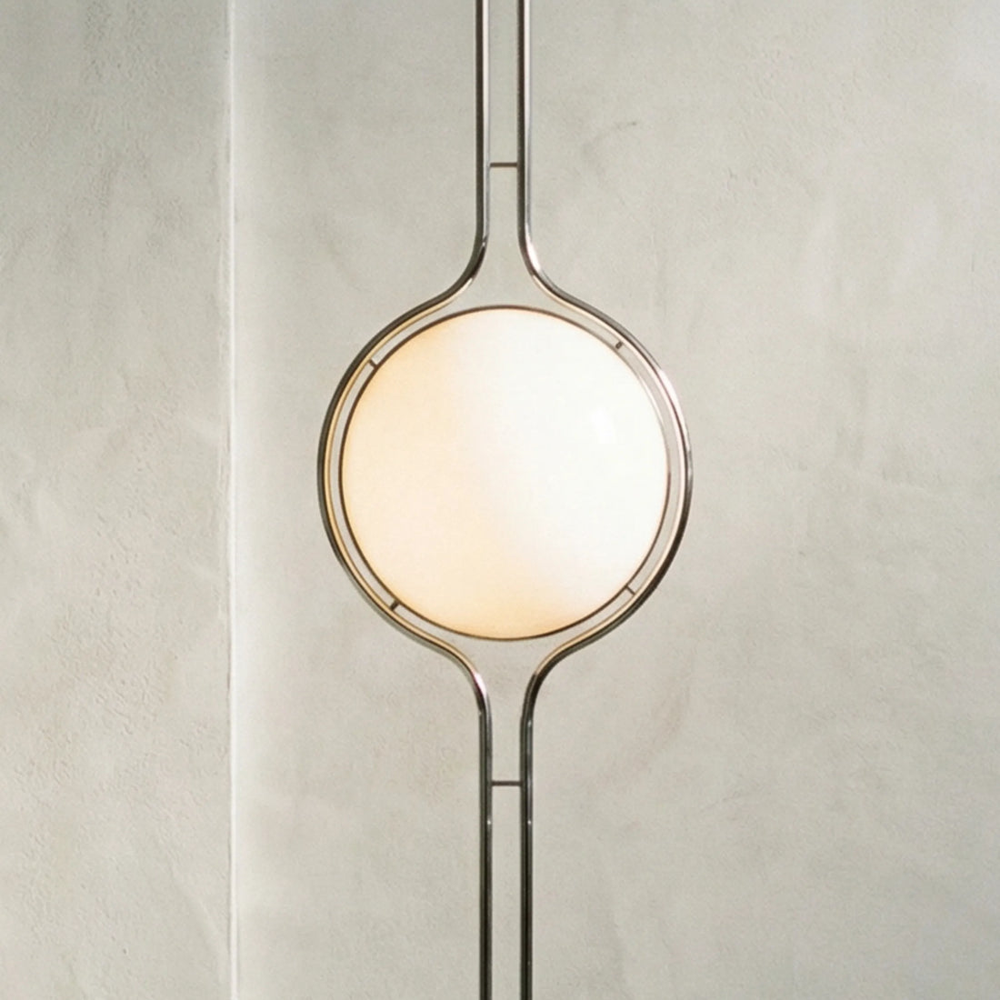 zuru floor to ceiling lamp close-up of lit frosted globe and chrome frame on textured wall