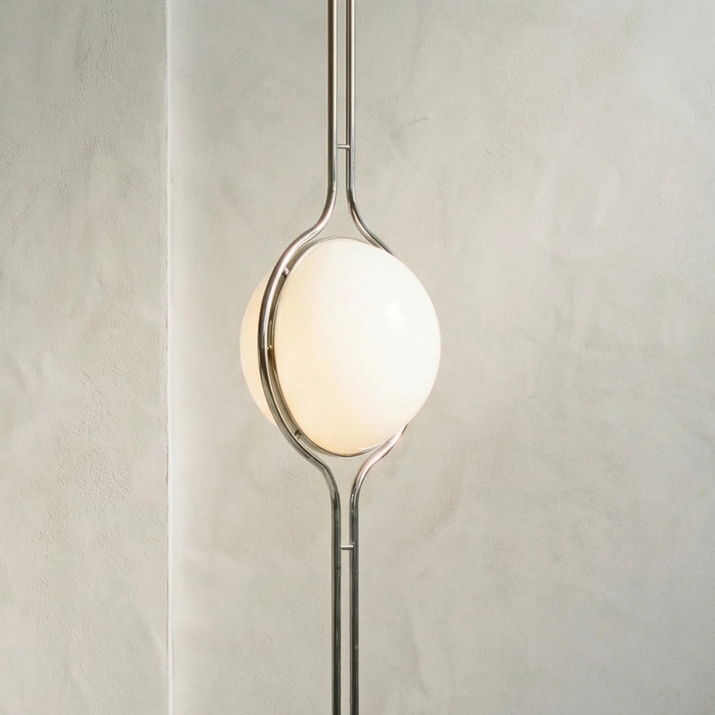 zuru floor to ceiling lamp side close-up of lit frosted globe and chrome frame on textured wall