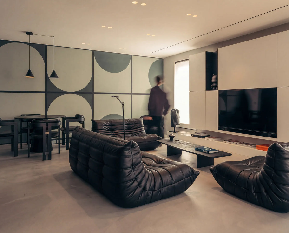 Dark upholstered Bruma seating around a low coffee table in a living room with a geometric feature wall.