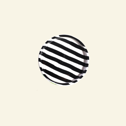 Black and white striped artisan handmade ceramic plate on a beige background