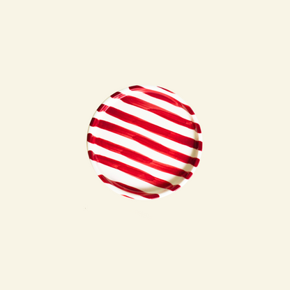 Red and white striped artisan handmade ceramic plate on a beige background