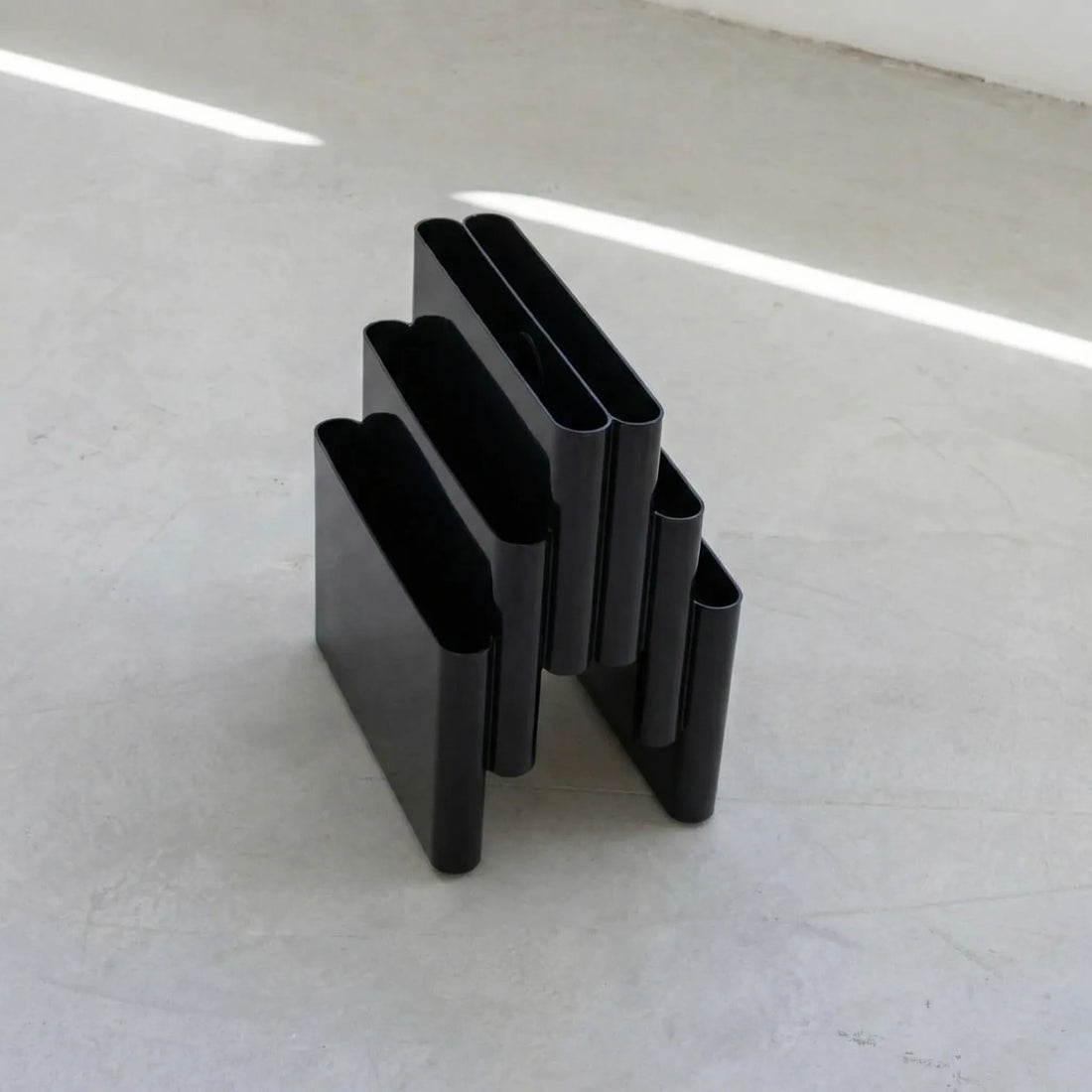 Black kartell magazine rack stand dupe on a white surface