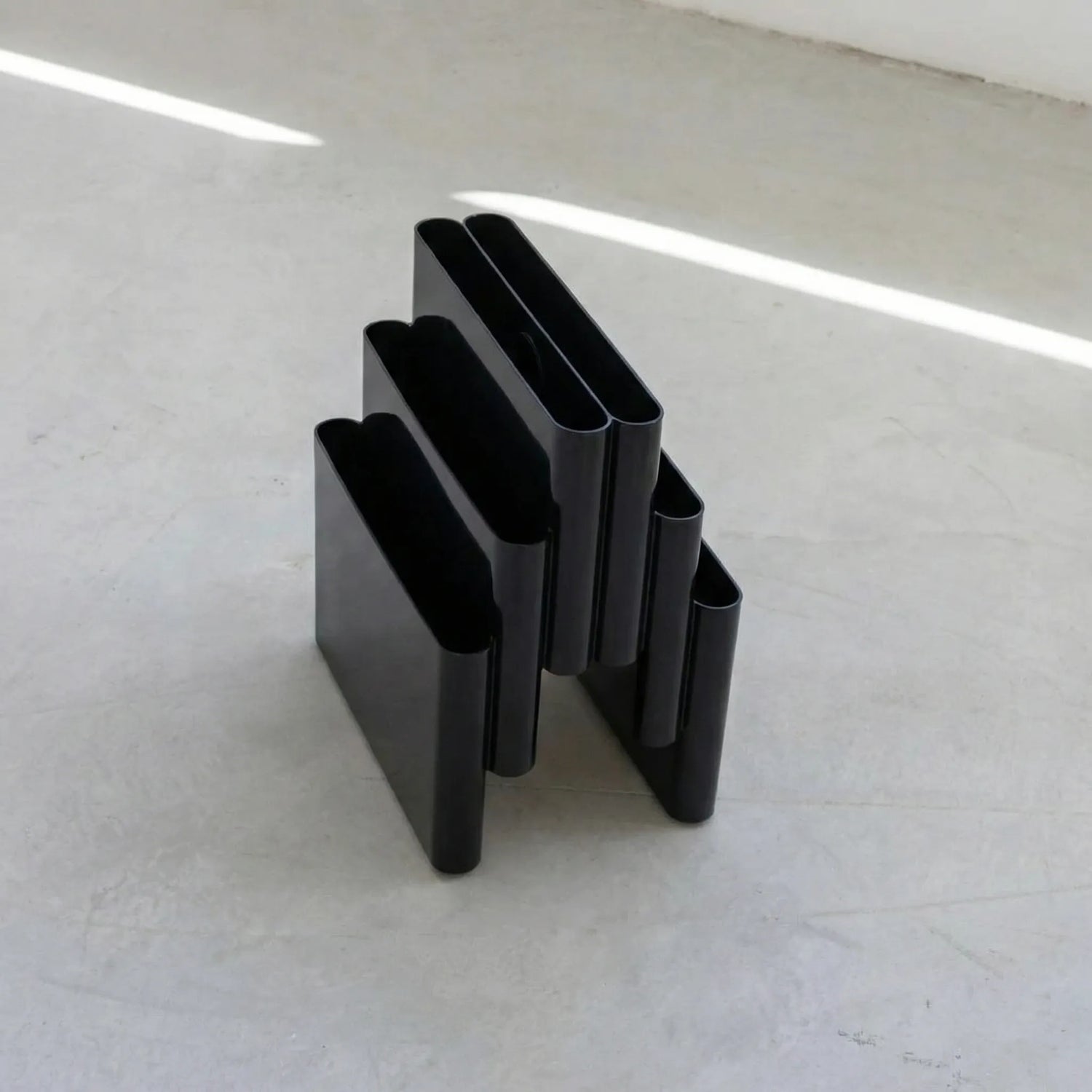 Black kartell magazine rack stand dupe on a white surface