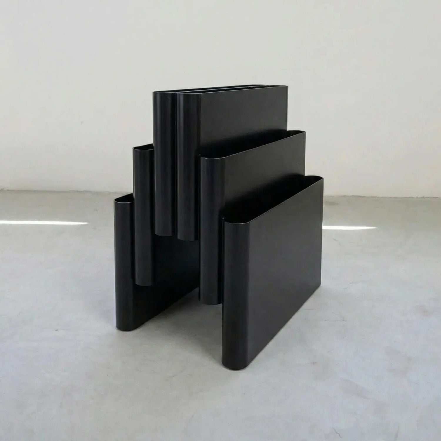 Black kartell magazine rack replica on a white surface