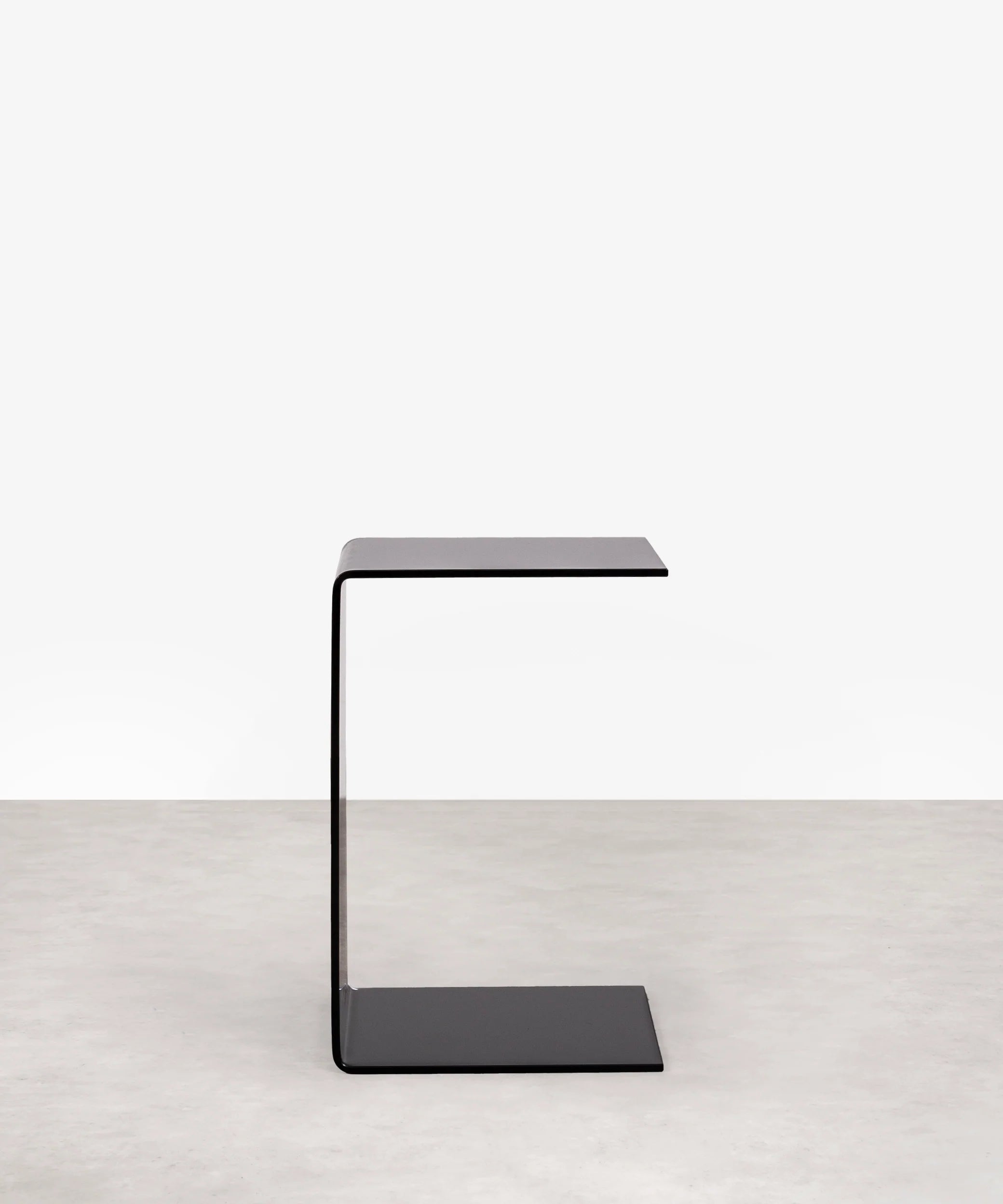 Modern grey c-shaped side table on a white background