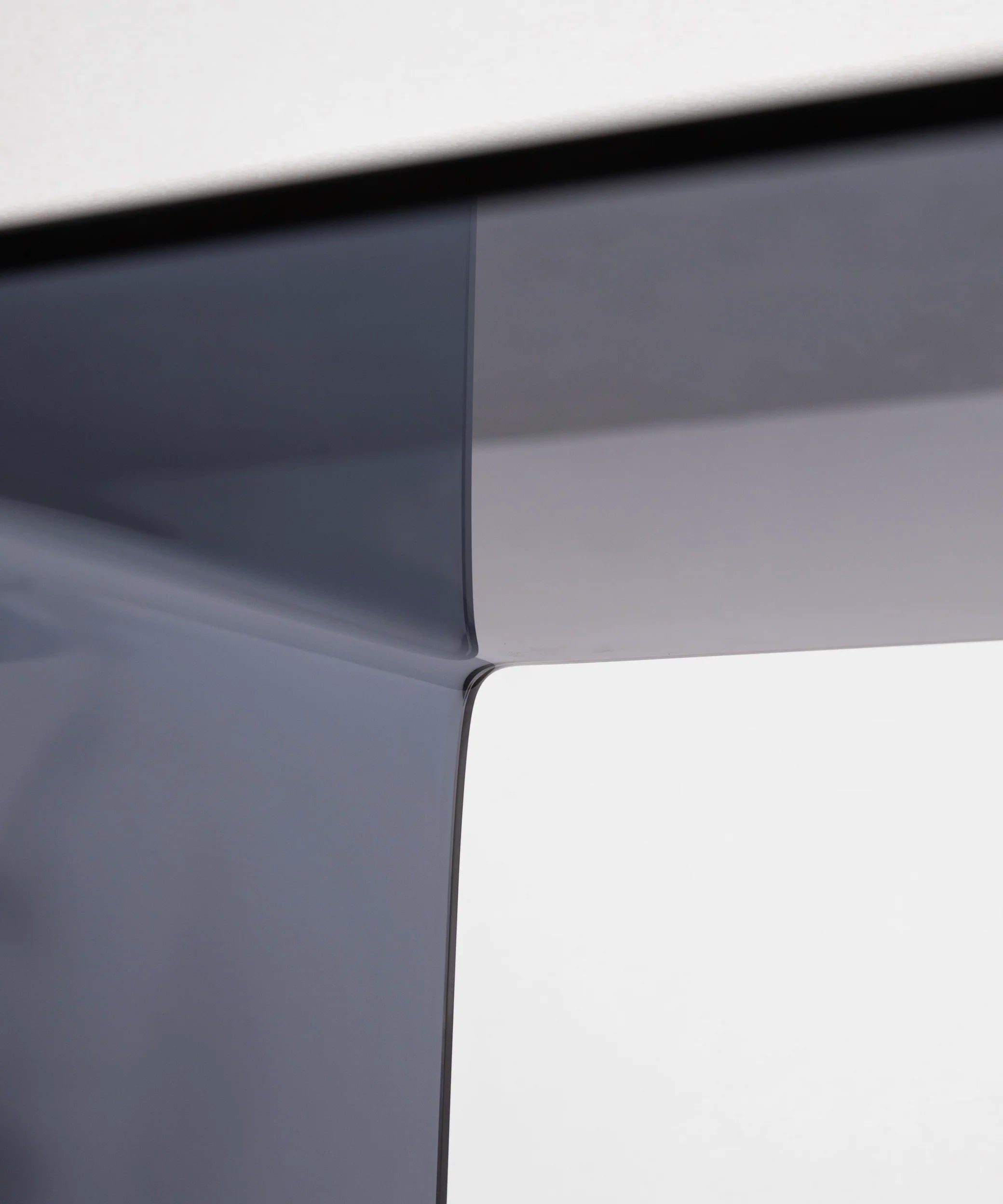 Close-up of the c-shaped side table in grey by vibehaus showcasing craftsmanship and material detail of designer couch table in acryl.