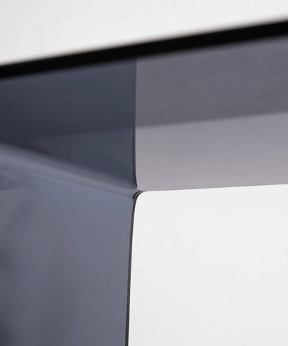 Close-up of the c-shaped side table in grey by vibehaus showcasing craftsmanship and material detail of designer couch table in acryl.