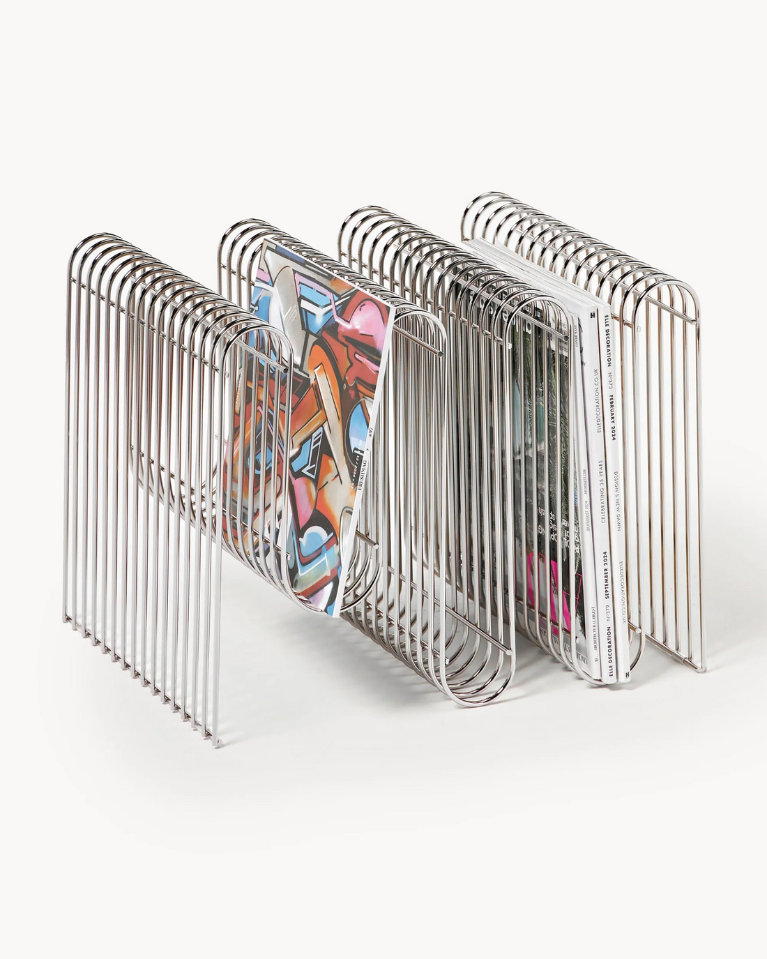 Metal magazine rack holding colorful books on a white background