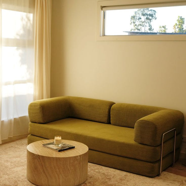 Green sofa in a room with a window and curtain