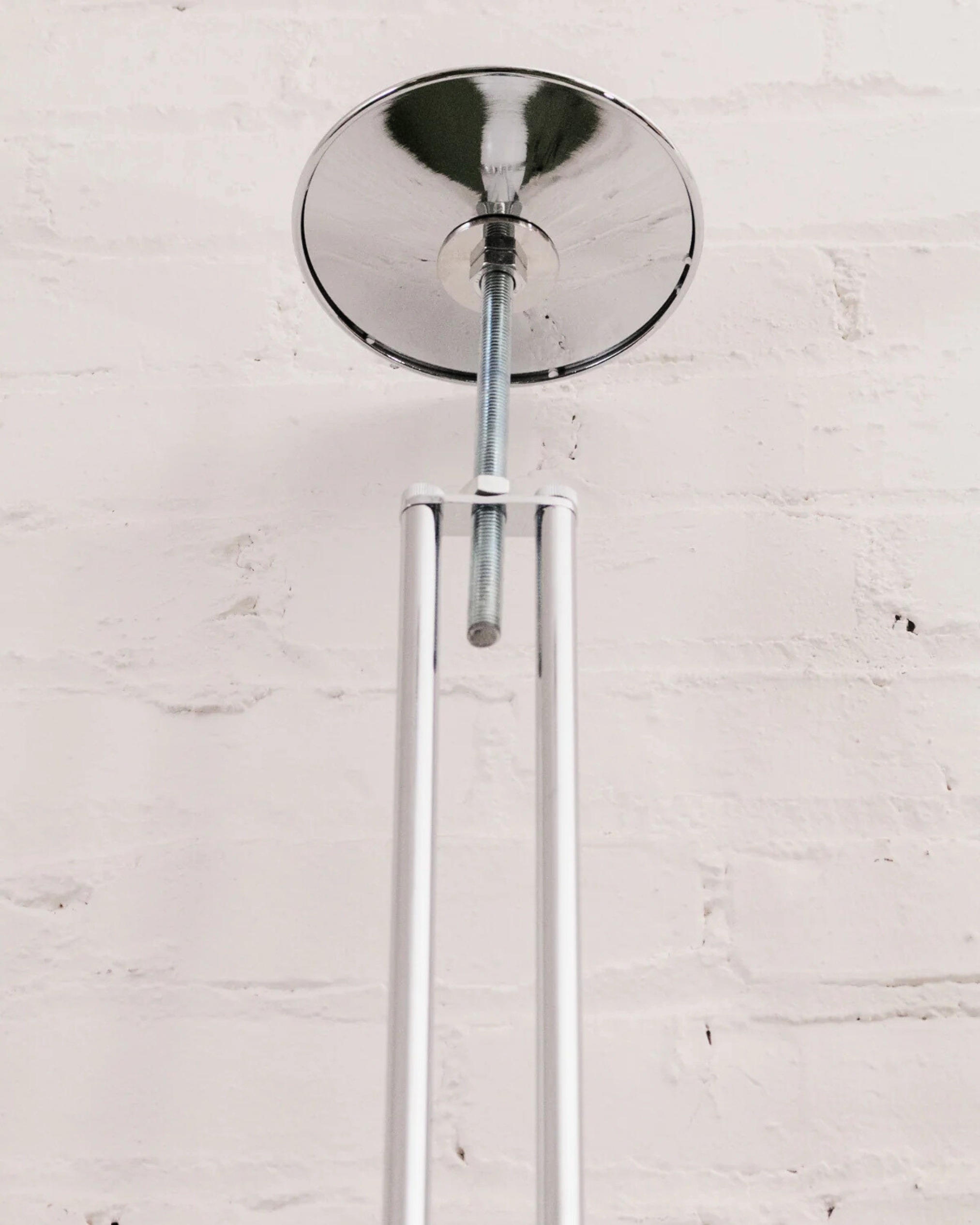 Chrome ceiling light fixture of the floor to ceiling globe lamp on a white brick wall background