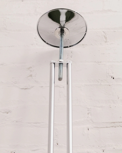 Chrome ceiling light fixture of the floor to ceiling globe lamp on a white brick wall background