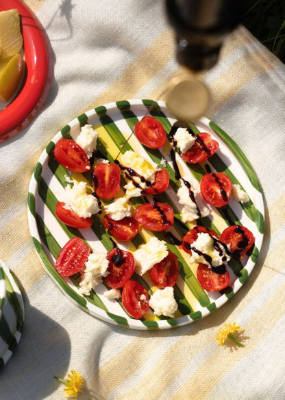 Plated salad with tomatoes and cheese on a Green-White striped artisan handmade ceramic dinner plate.