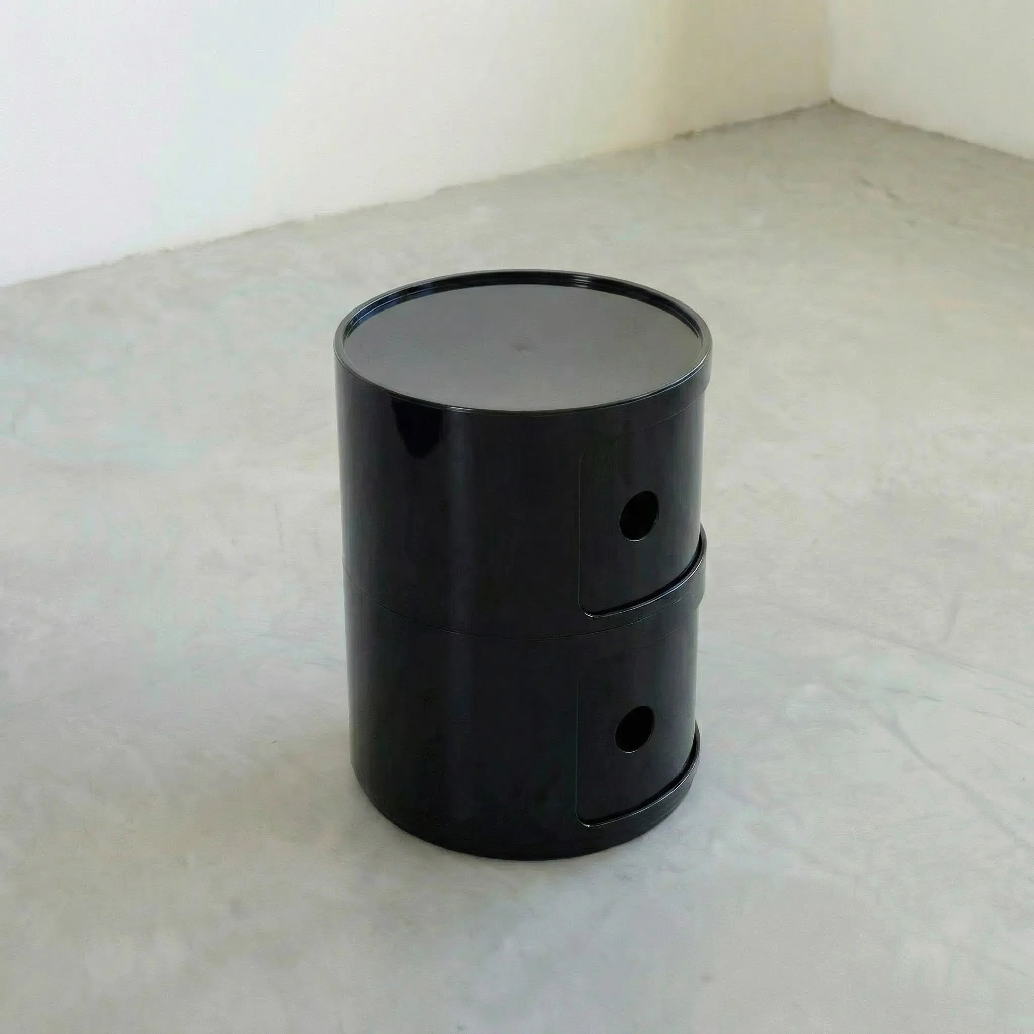 Black glossy round modular storage unit, Kartell Componibili dupe with two tiers in minimalist concrete studio