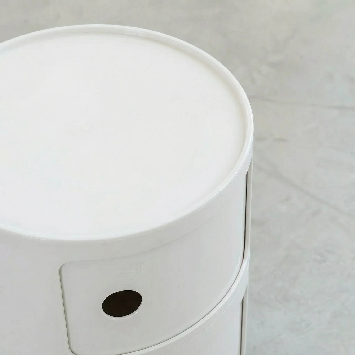 Close up of the Kartell Componibili dupe round modular storage unit in white glossy plastic with two tiers on concrete floor in white studio