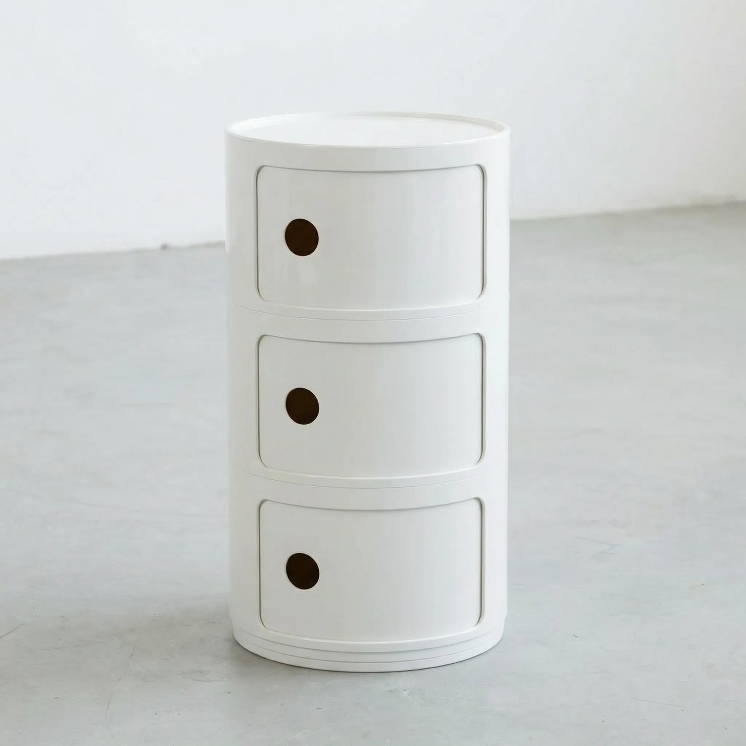 Kartell Componibili dupe round modular storage unit in white glossy plastic with three tiers on concrete floor in white studio