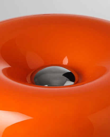 Close-up of a bright orange donut lamp with a reflective center on a gray background