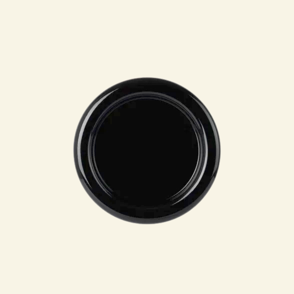 Round chunky thick ceramic plate in black  on a beige background