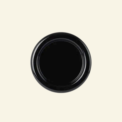 Round chunky thick ceramic plate in black  on a beige background
