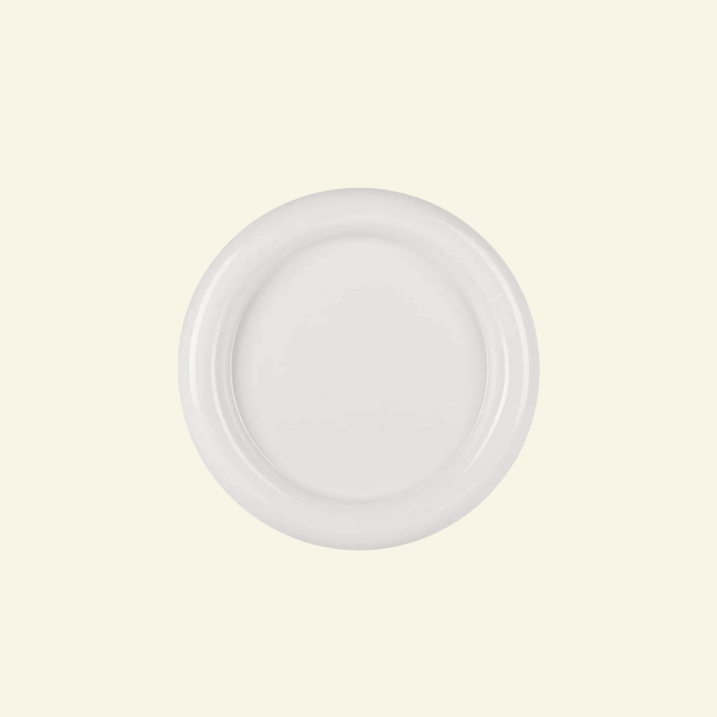 Round chunky thick ceramic plate in white  on a beige background
