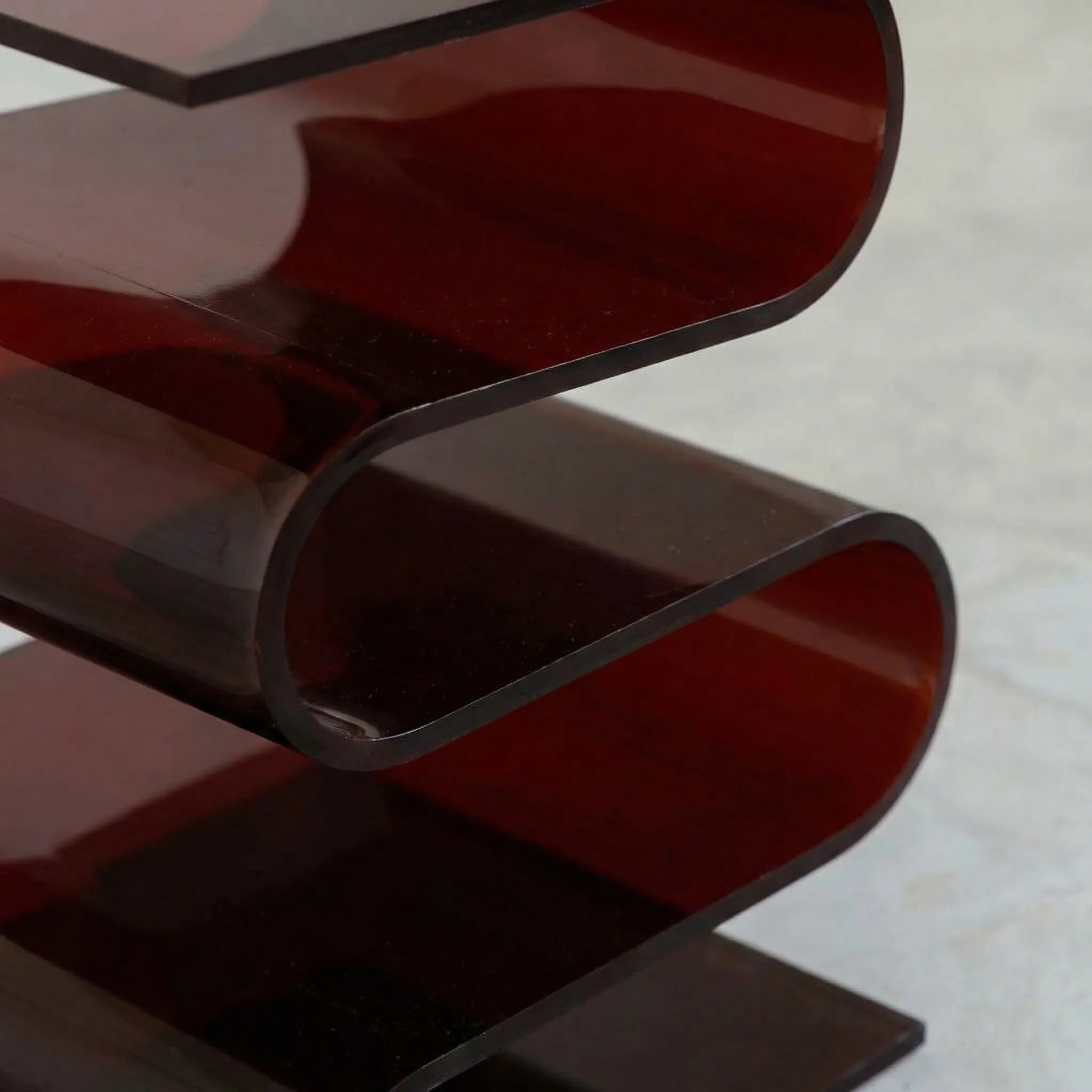 Close up of the Acrylic S Shaped Side Table in amber red  by Vibehaus