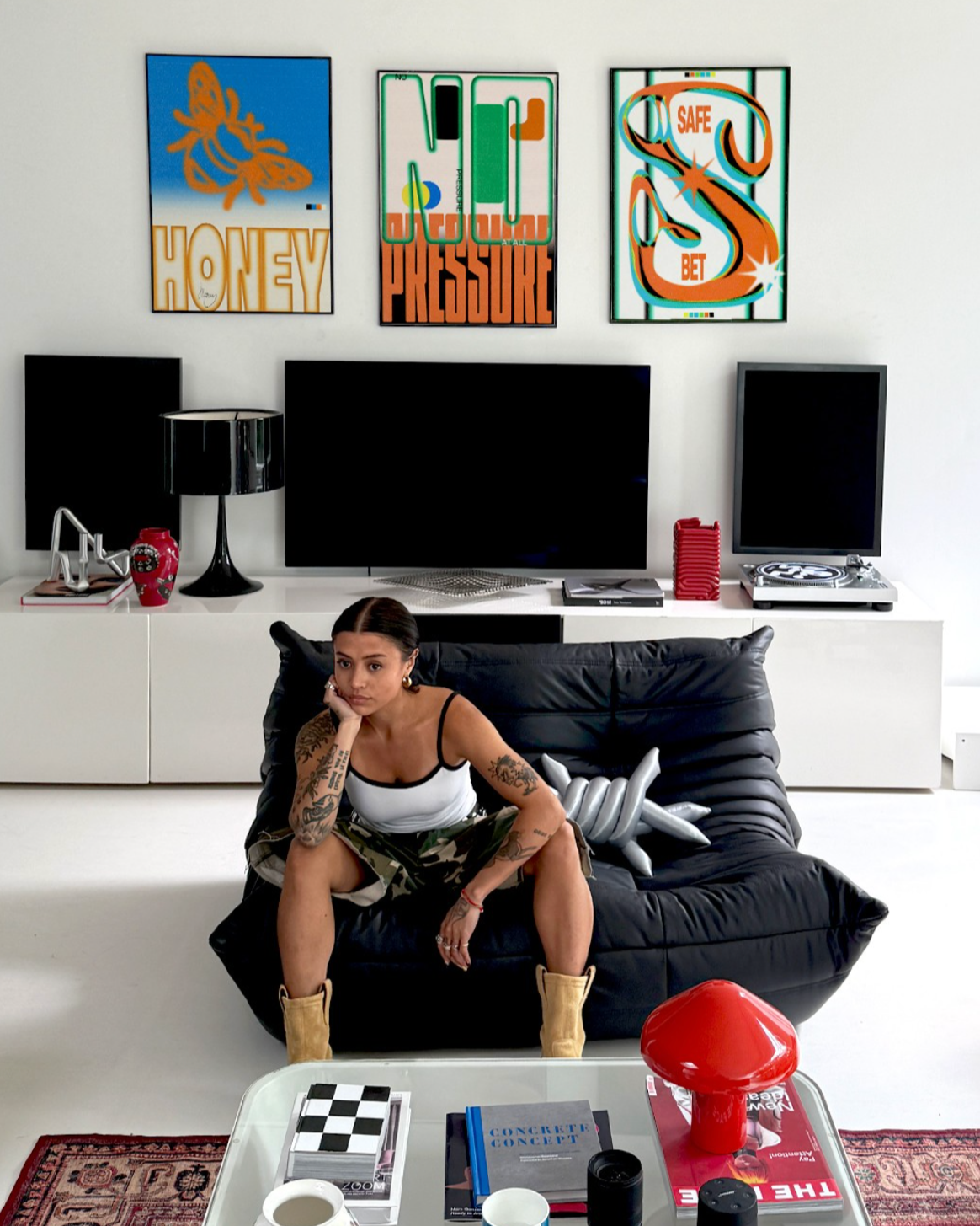 Woman sitting on a  Togo black leather 2-seater dupe  in a modern living room with colorful wall art.