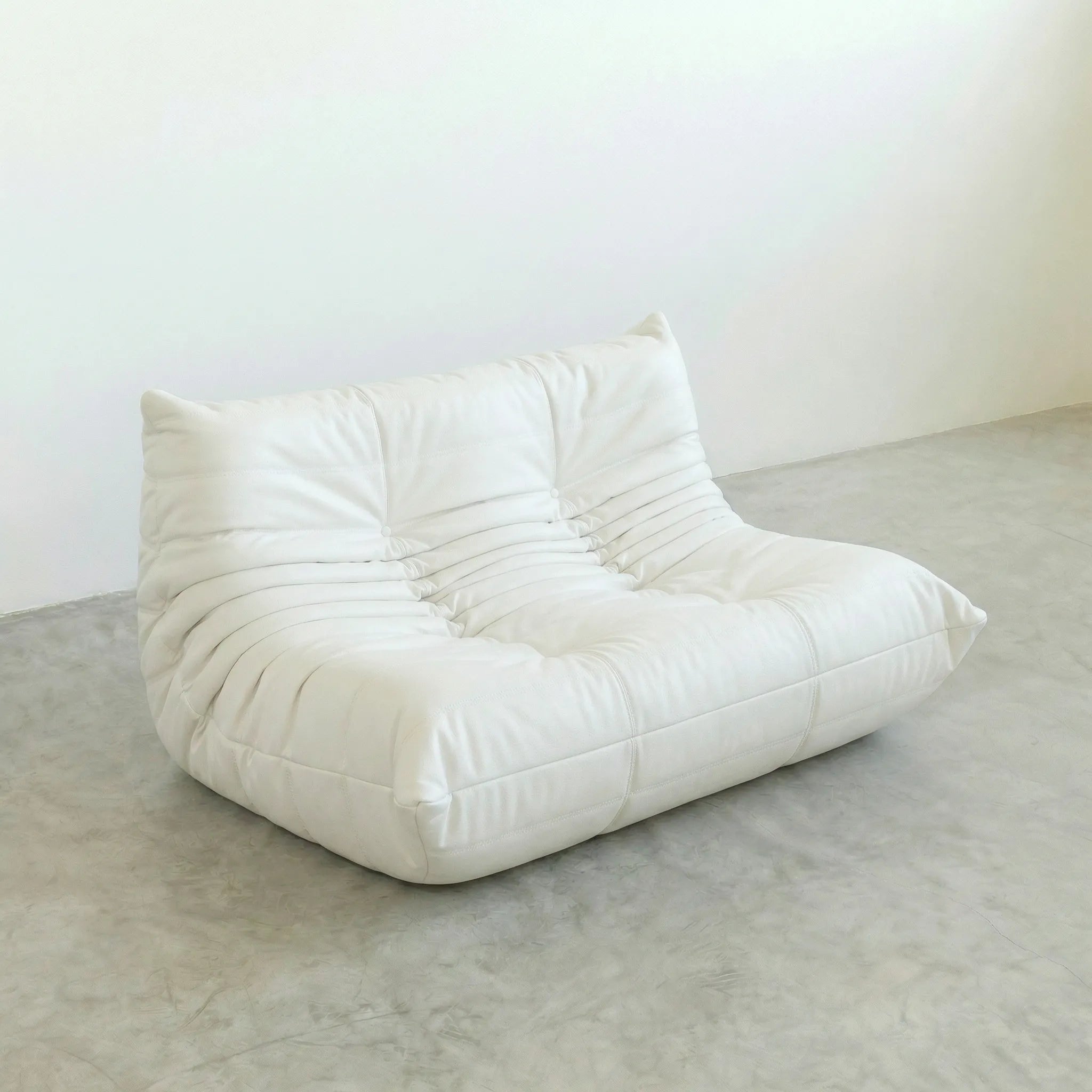 White togo leather sofa dupe on a gray floor with a white wall background