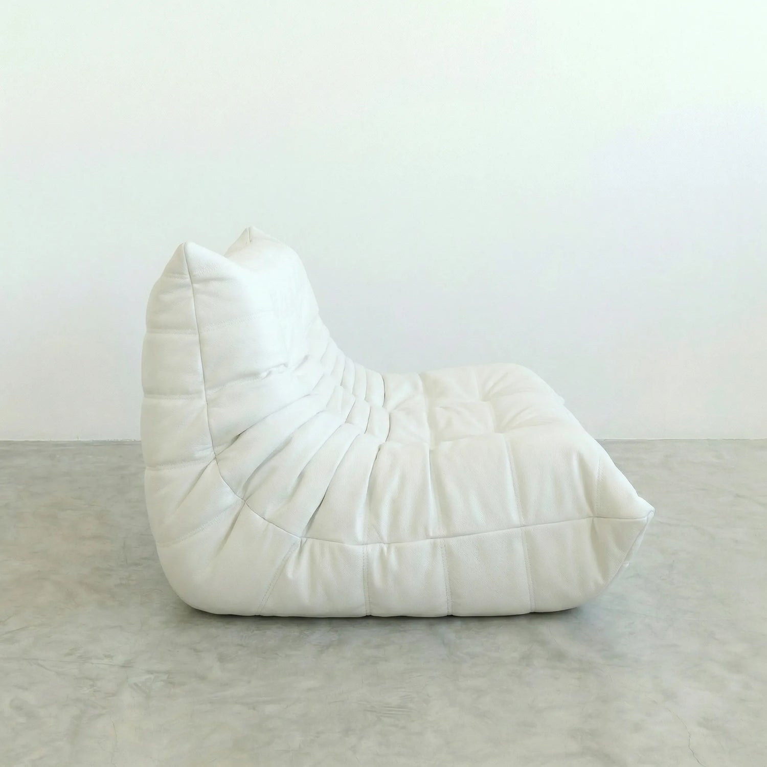 White togo leather sofa dupe on a gray floor with a white wall background