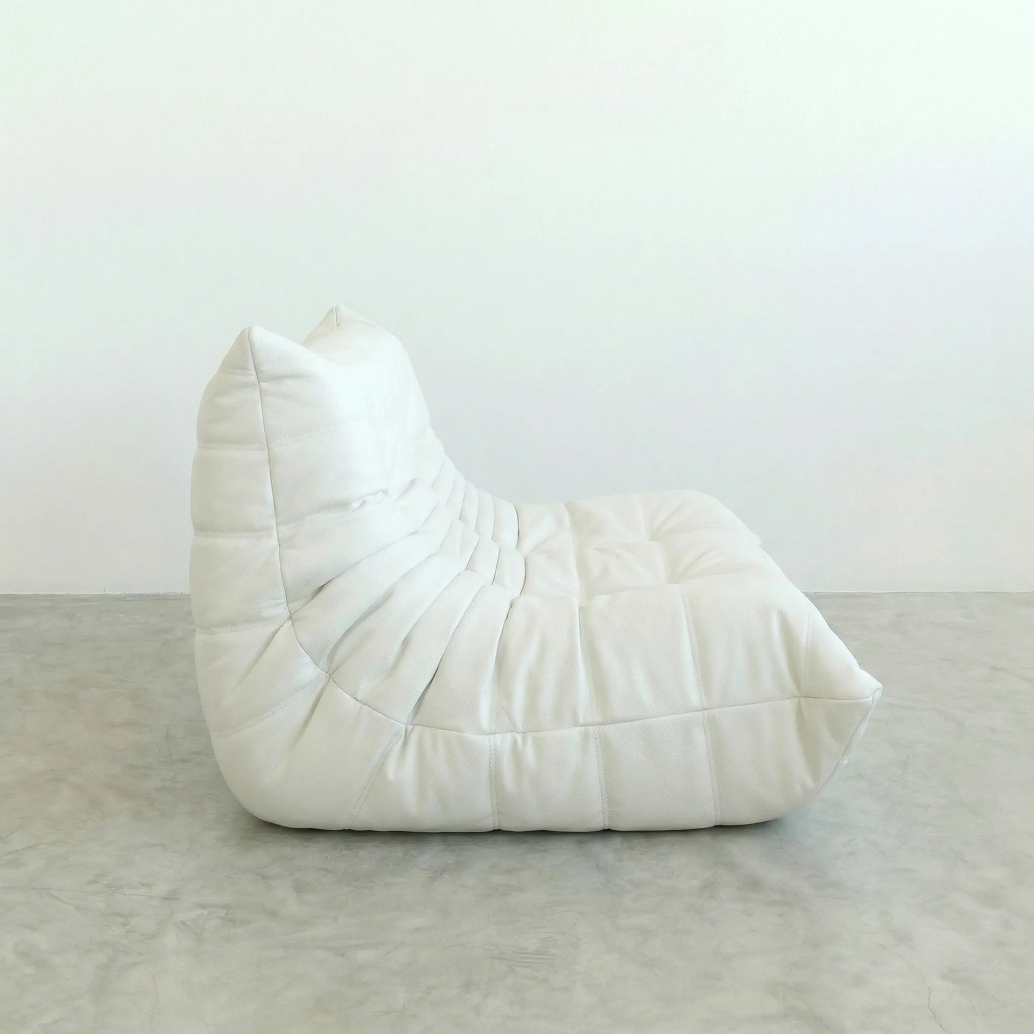 White togo leather sofa dupe on a gray floor with a white wall background