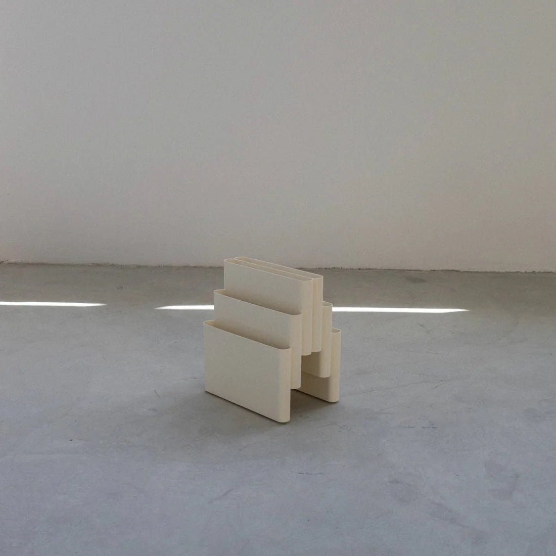 White Kartell magazine rack replica on a white surface