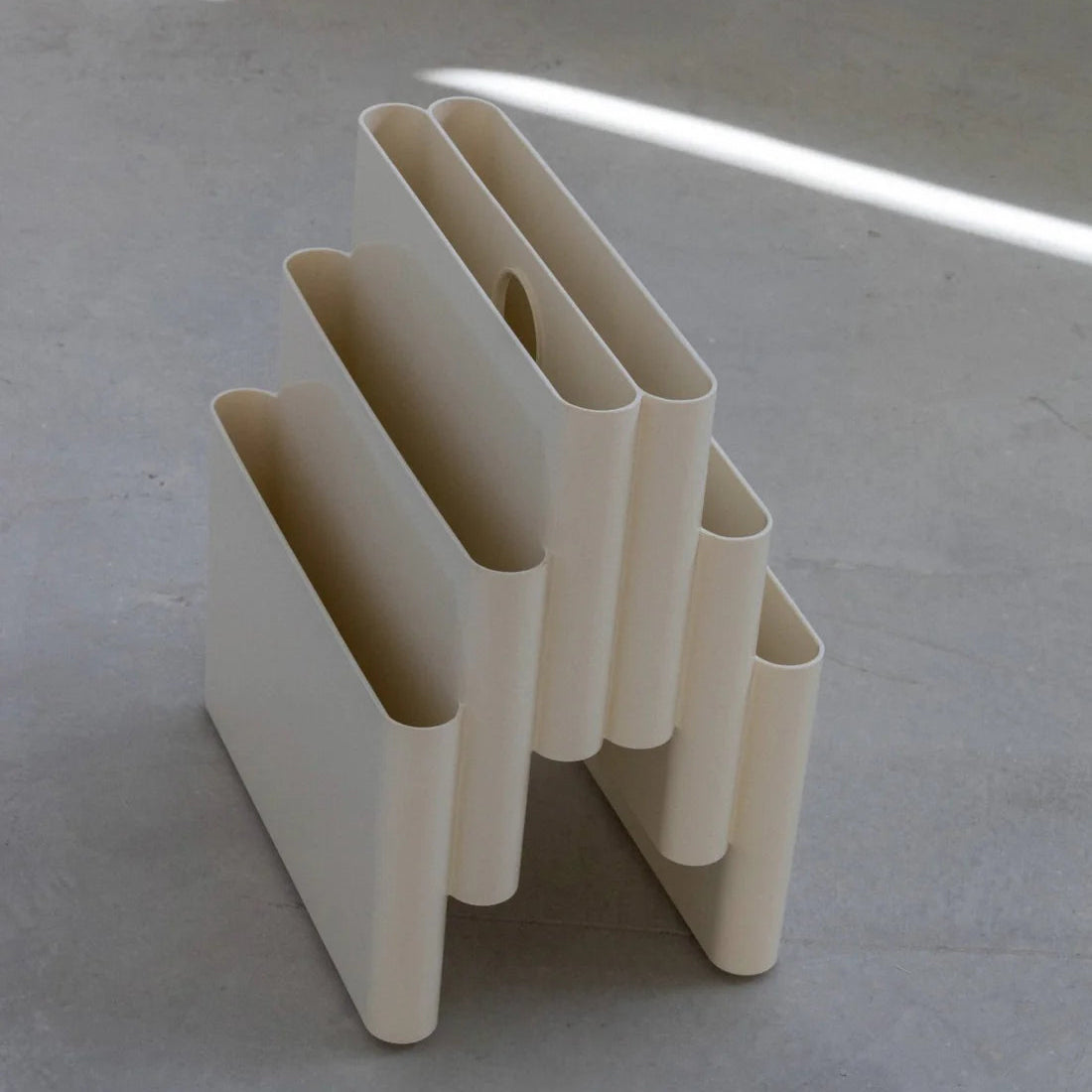 White Kartell magazine rack replica on a white surface