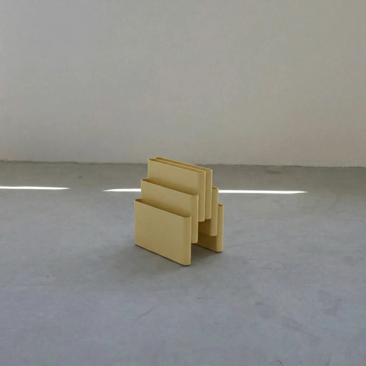 Yellow Kartell magazine rack replica on a white surface