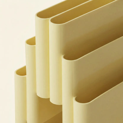Close up of the Yellow Kartell magazine rack replica on a white surface