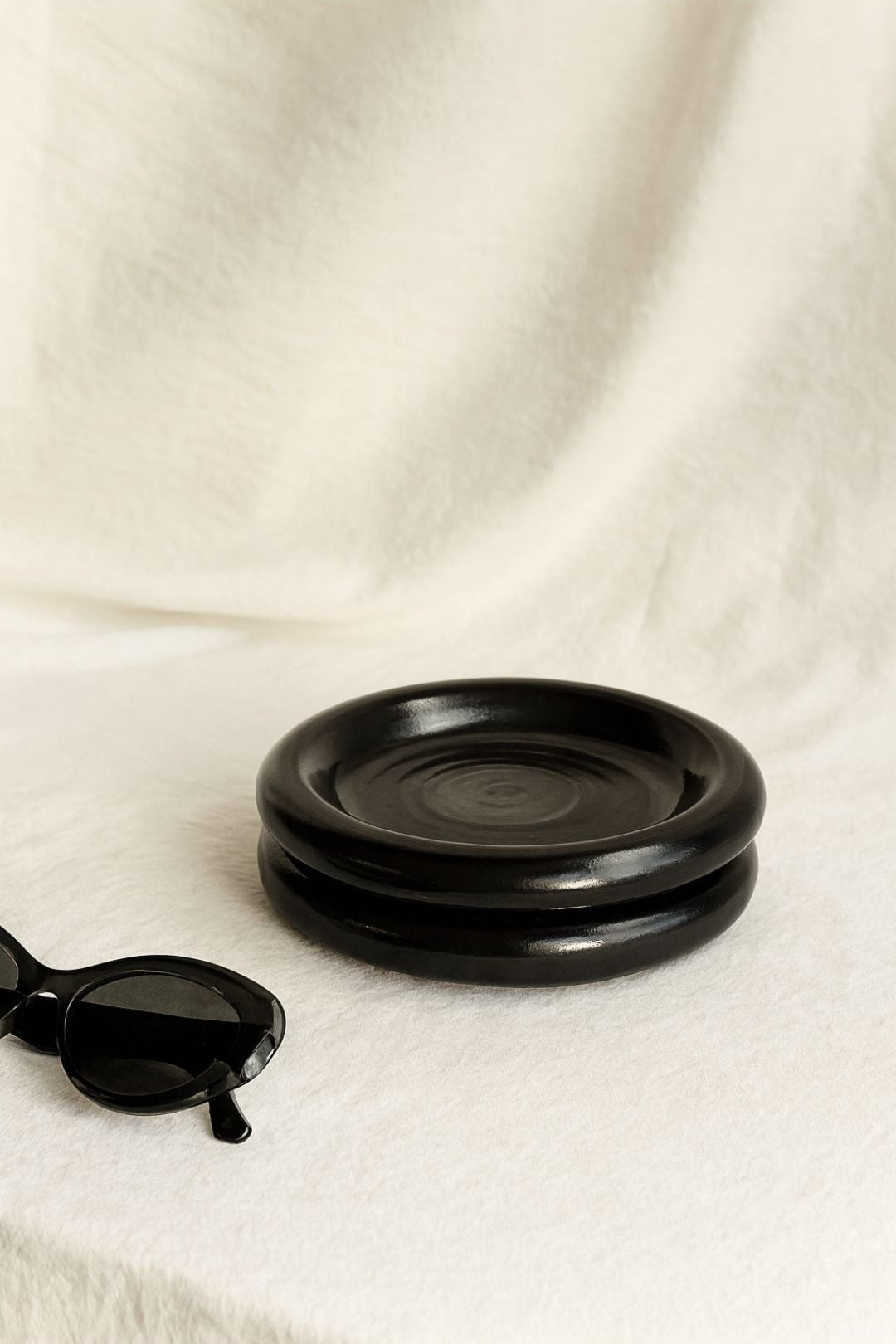 Cozy breakfast setup with Gustaf Westman–inspired black chunky ceramic plate on the white table with sunglasses