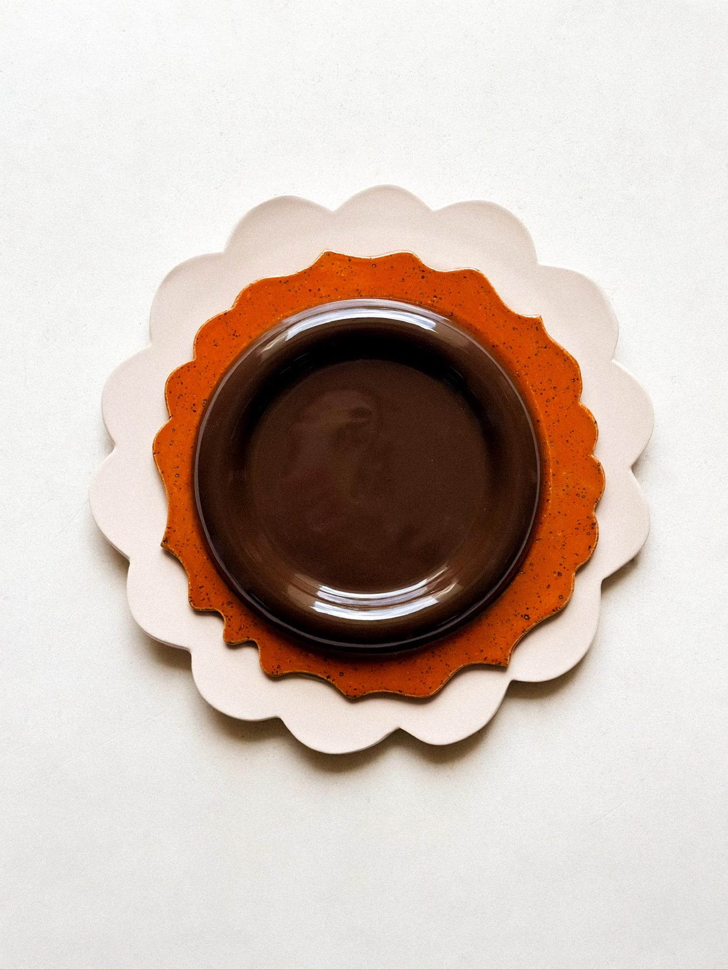 Decorative brown ceramic plate with thick chunky border rim on a white background