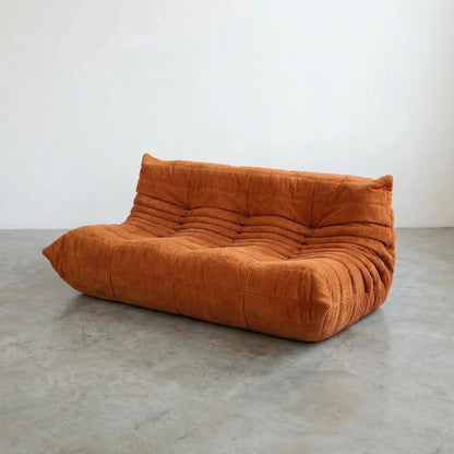 Orange corduroy Bruma 3 seater sofa on a concrete floor
