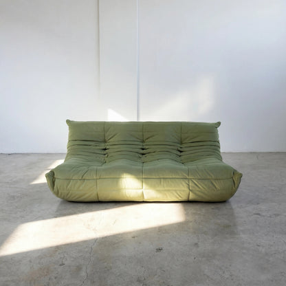 Bruma 3 seater sofa in Green Velvet Suede by vibehaus on a concrete floor, photographed from a front angle.