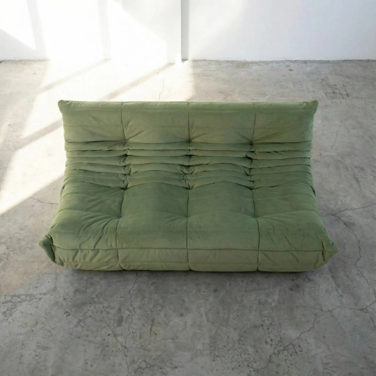 Bruma 3 seater sofa in Green Velvet Suede by vibehaus on a concrete floor, photographed from a top angle.