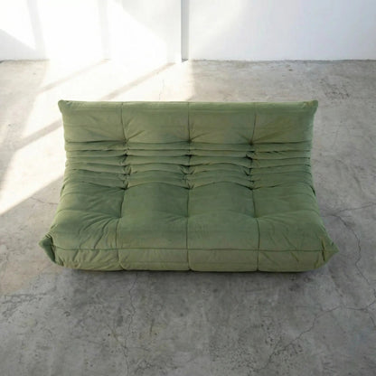 Bruma 3 seater sofa in Green Velvet Suede by vibehaus on a concrete floor, photographed from a top angle.
