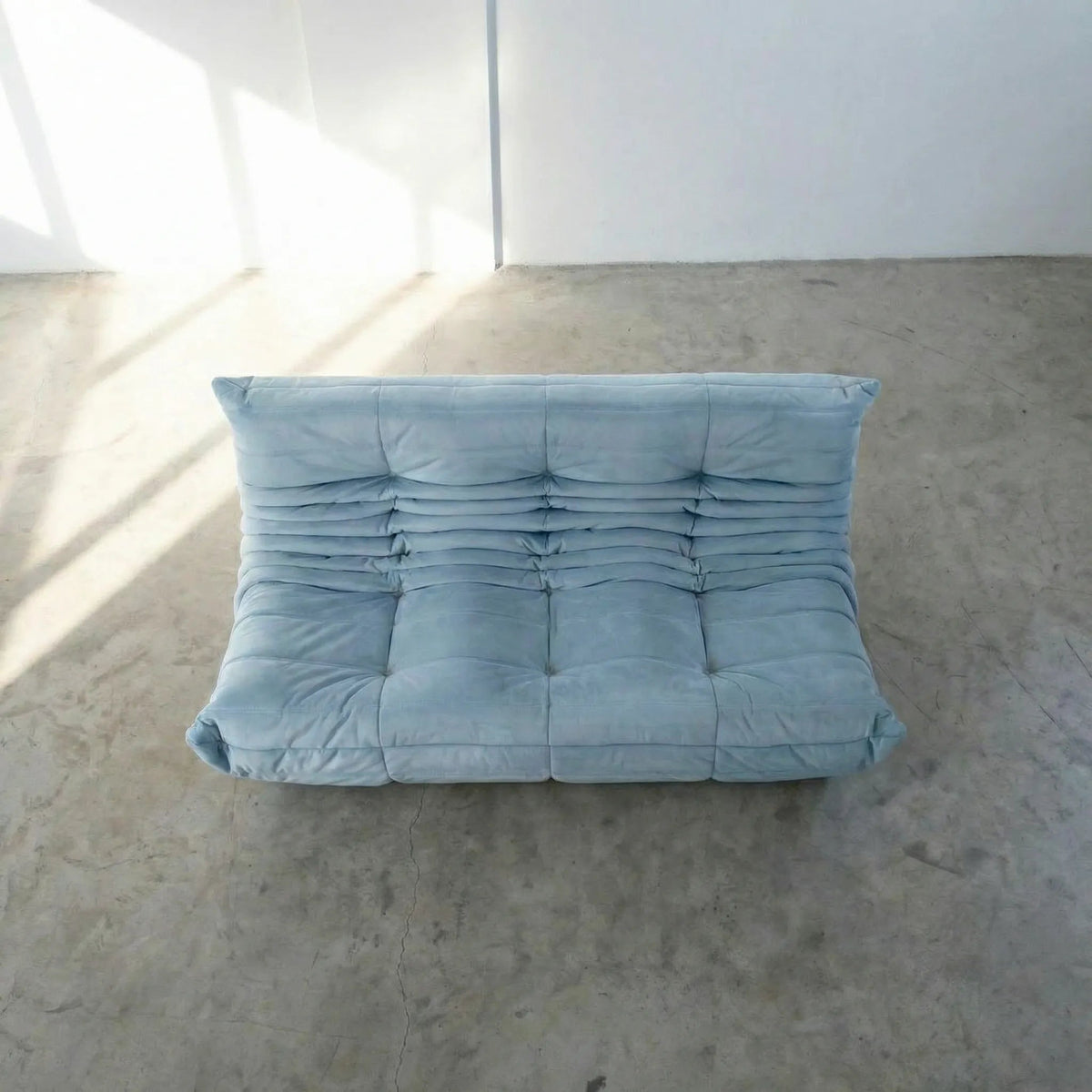 Bruma 3 seater sofa in light blue Velvet Suede by vibehaus on a concrete floor, photographed from a top angle.