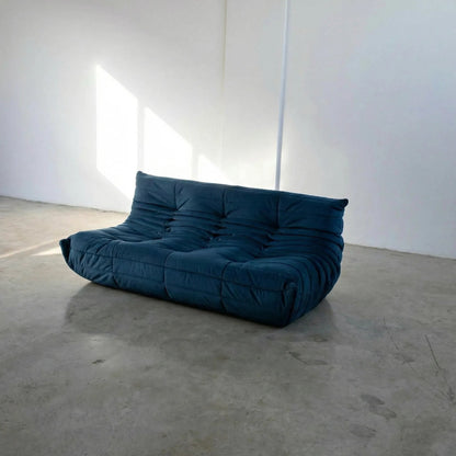 Bruma 3 seater sofa in dark blue Velvet Suede by vibehaus on a concrete floor, photographed from a side angle.